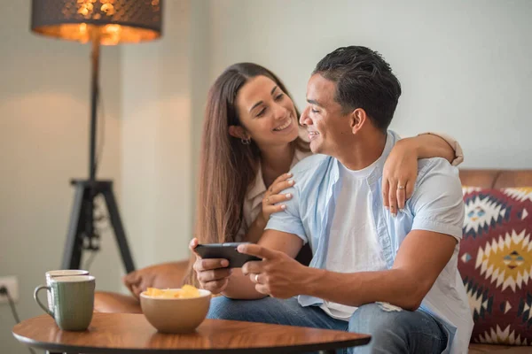 在现实生活中 一对年轻夫妇在家里 在沙发上休闲放松 并使用手机应用程序 现代男孩和女孩一起住在公寓里 关系和约会生活方式 — 图库照片