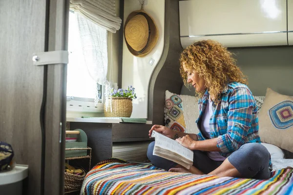 一位妇女坐在一辆现代野营车的车内看书 独自享受室内休闲活动的乐趣 独立的女士过着远离格栅的虚荣生活 旅行和人员放松 — 图库照片
