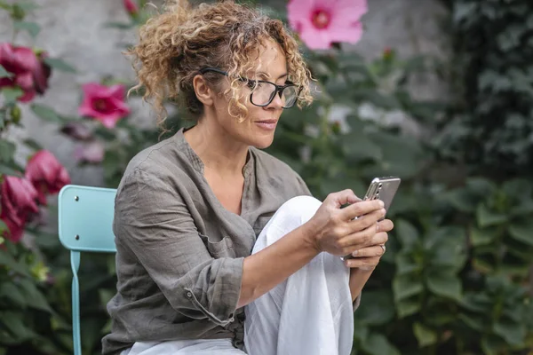 Mujer Usando Teléfono Móvil Aire Libre Concentrado Con Plantas Flores —  Fotos de Stock