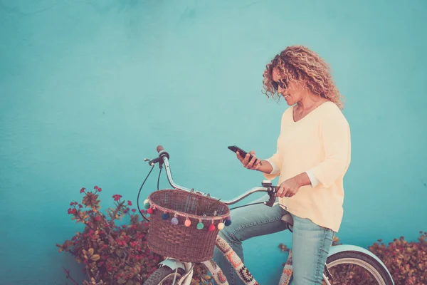 Widok Boku Kobiety Jadącej Rowerze Tle Niebieskiej Ściany Korzystającej Telefonu — Zdjęcie stockowe