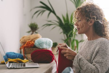  Evde hobi yapan bir kadın dizüstü bilgisayardan özel ders izliyor. İnternet 'te modern sınıf dersleri. Teknoloji ve kapalı alan aktivitesi insanları. Uzaktan kumanda. E-öğrenim gören yetişkin kadın.