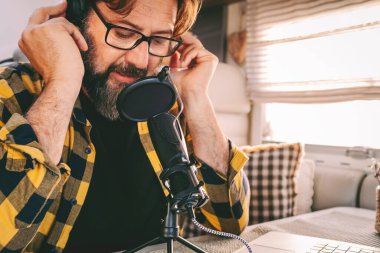  Kapalı alanda mikrofonda konuşan adam. Podcast yeni iş fırsatı konsepti. Modern olgun insanlar radyo kanalında konuşuyor. Akıllı çalışma ya da dijital göçebe yaşam tarzı için yeni iş fırsatı