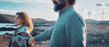 Seyahat eden bir çift, gün batımının tadını çıkarır. El ele tutuşup, önlerine bakarlar. Gezgin yaşam tarzında aşk ve ilişki. Seyahat tutkusu. Sahil okyanusu ve arka planda mavi gökyüzü olan yel değirmenleri. Yaşam