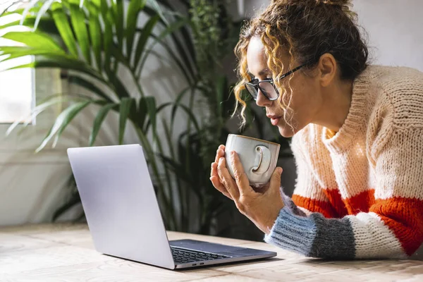 オフィスでノートパソコンだけで若い成熟した起業家の肖像 健康的なライフスタイルのためのお茶を飲む 眼鏡をかけ ワイヤレス接続でコンピュータ上でネットサーフィンをしている女性 — ストック写真