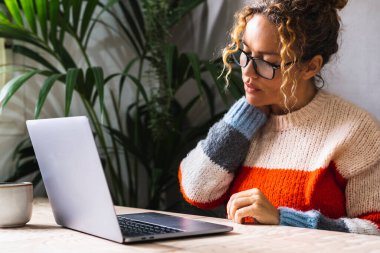 Yorgun bir kadın, dizüstü bilgisayar kullanırken boynuna dokunup kaslarını geriyor. Masa başı iş yeri konsepti sağlığında kötü bir duruş. Bilgisayarın önünde omuzlarına masaj yapan bir kadın. Kötü alışkanlıklar.