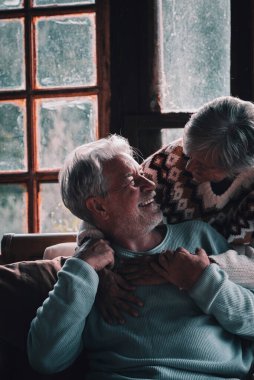 Romantik, son sınıf çifti evde oturup birbirlerine gülümseyerek ve romantizmle sarılıyorlar. Emekli, sağlıklı, mutlu yaşam tarzı insanlar. Chalet kış tatili kavramı