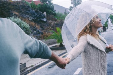 Mutlu çift şemsiye kullanarak yağmurun altında birlikte vakit geçirmenin ve dışarıda eğlenmenin tadını çıkarıyor. Pov adam kadın elini tutuyor. Mutluluk ve huzurlu bir hayat. Sokakta yürüyen insanlar