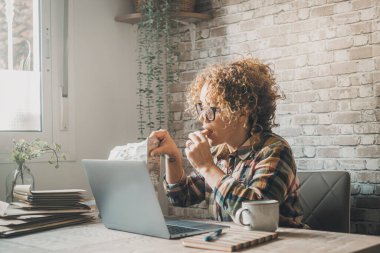 Ev ofis işyerinde yeni iş hayatı kavramı. Kadın aynı anda hem çalışıyor hem de kurabiye yiyor. İşadamları, bilgisayar kablosuz bağlantısını kullanarak kapalı alanda tek başlarına çalışmakla meşgul.