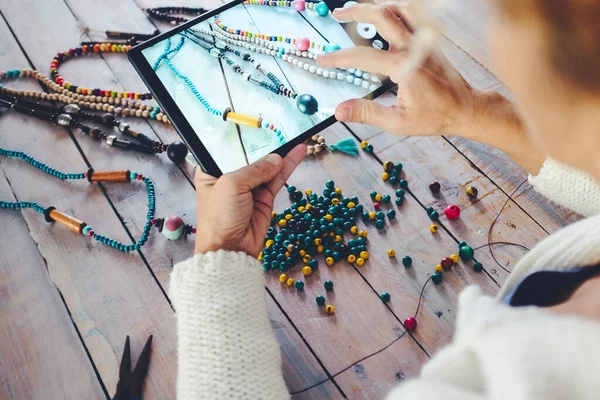  Kadın renkli boncuklarla el yapımı resimlerini çekmek için tablet kullanıyor. Kolye yapmak ve internette ürün satmak. Modern yeni iş konsepti mağazası ve ekonomi. Alternatif görev