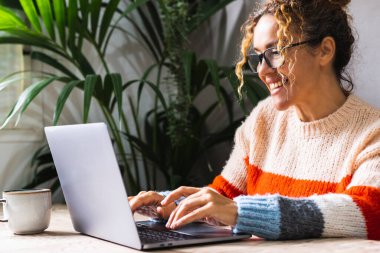 Home work and happiness concept lifestyle.  woman adult wearing eyewear and writing on laptop at the office. Modern business. Online job female people using computer in indoor leisure activity clipart
