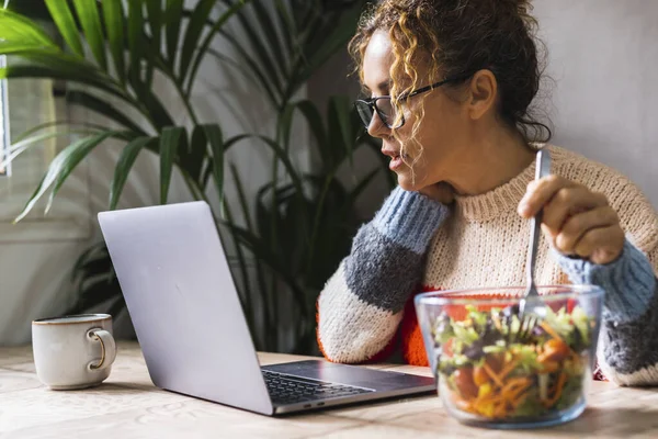 女性忙于工作 一边吃着健康的沙拉 一边在电脑上工作 上班时间的午休时间 健康的女性生活方式 办公室家庭工作场所 — 图库照片