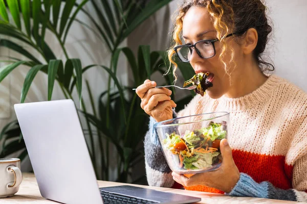 年轻员工在快餐时间吃沙拉 同时在笔记本电脑上不停地工作 忙碌的女商人吃着健康的东西 在桌子上使用笔记本电脑 办公室和业务 健康生活方式工作 — 图库照片