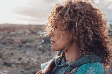 Uzun, güzel kıvırcık saçlı bir kadının yan portresi açık hava aktivitesinin tadını çıkarıyor. Seyahat ve macera, insanların yaşam tarzı. Seyahat eden bir yetişkin kadın çöl deneyimi.