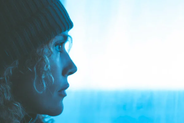 Mavi Işıkta Pencereden Dışarı Bakan Örgü Şapkalı Kadın Portresi Seyahat — Stok fotoğraf