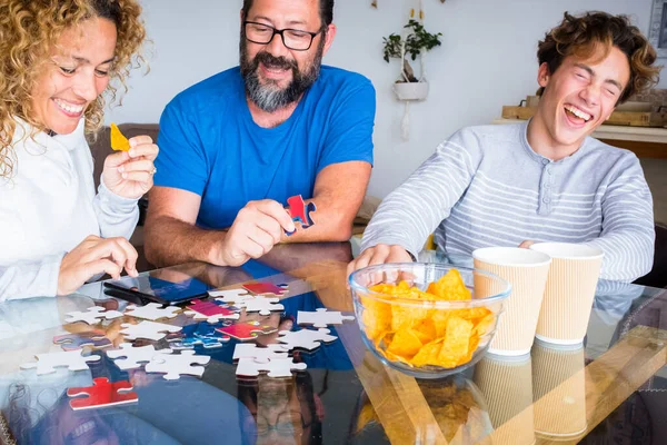 Happy real people family play together with cards at home on the table, laughing and having fun. Man and woman father mother with son enjoy time in playful indoor leisure activity on sunday holiday
