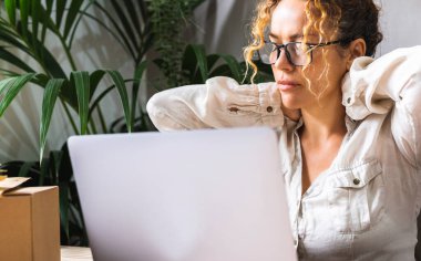 Yorgun iş kadınını bilgisayarın önünde kapat. Yorgun kadın çalışan online iş. Bir kadın dizüstü bilgisayarın önünde boynuna dokunup masaj yapıyor. Küçük işletme uzun proje konsepti.