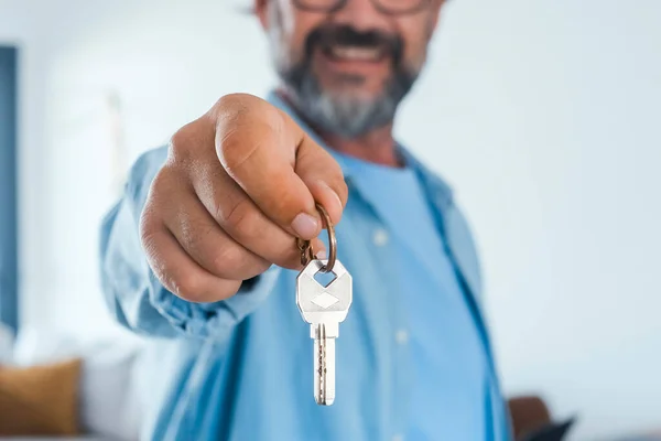 Close up of new home keys. happy man smile and show at the camera his house key. Real estate and apartment business investment business activity. Moving mortgage loan banking concept. Booking.