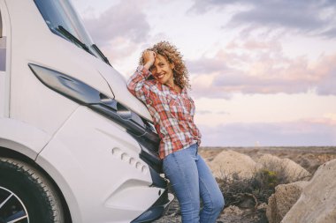  Tek başına gezen kadın gülümseyecek ve kameraya bakacak. Büyük, modern bir karavan karavanına bakacak. Seyahat ve varış yerinin keyfini çıkaracak. Alternatif ev vanlife tarzı insanlar. Yolculuk nereye?
