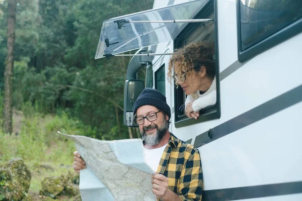 happy traveler couple looking together a paper guide map to choose plan next travel destination. Living in a van. Nomadic people, Vanlife. Alternative vehicle vacation journey. Road trip planning