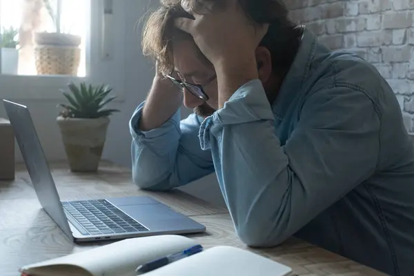 心配して絶望的な労働者は疲れ果てた表情で頭を抱えている机の労働者を強調した オンラインラップトップコンピュータの前で問題と破産のビジネスマンの小さなビジネスの側面のビュー — ストック写真