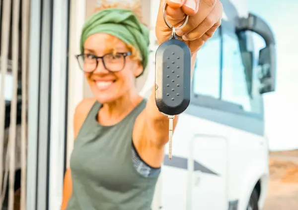 Happy new buyer owner of camper van motorhome show at the camera her keys with happiness. New house and vehicle for vacation concept scene. Travel vanlife lifestyle. Adventure. Nomadic people female
