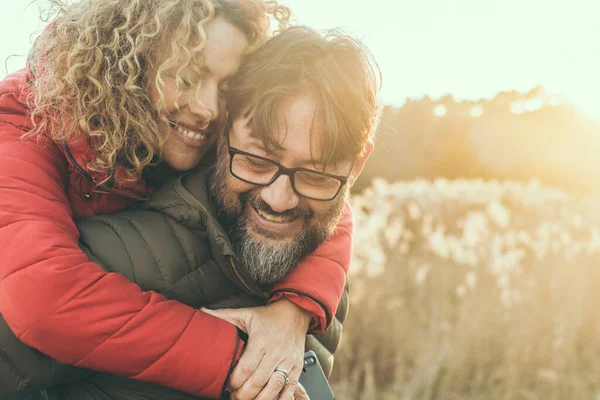 adult mature couple in love hugging and smiling with romance expression on face.  man carry woman in piggyback on his back. Female bonding male in outdoor leisure activity together. Happiness