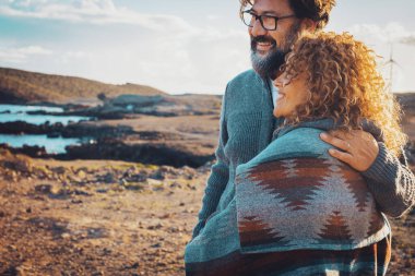 Mutlu gezgin yetişkin çift, aşk ve macera dolu yaşam tarzıyla birlikte çöl sahili sahil şeridinde boş zaman aktivitelerinin tadını çıkarıyor. Erkek, dışarıda mutlu insanları kucaklıyor.