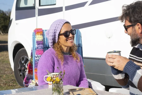 Travel and camping people lifestyle outdoor leisure. Couple with adult man and woman enjoying time together outside a camper van. Alternative tourism and home lifestyle people. Getting away. Freedom