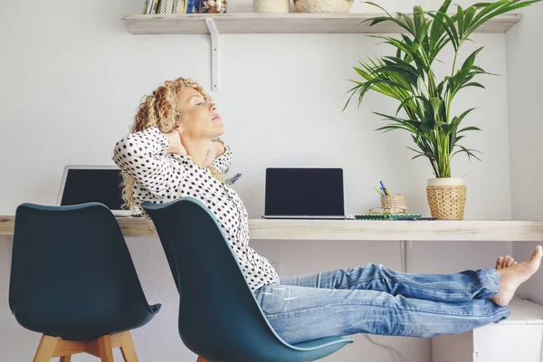一个女人在家里放松地坐在椅背和肩膀上 摸着脖子 人和放松下班后 背景中的笔记本电脑 在家庭技术领域工作 — 图库照片