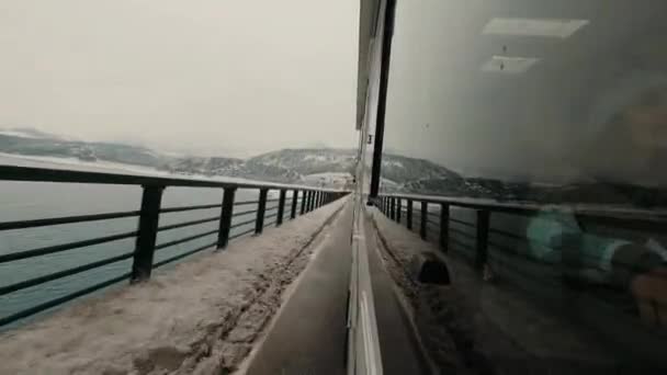 慢行车辆面包车越野车在外面的女乘客车窗视野中行驶在雪冬路上 玻璃上倒映着群山 旅行和度假的概念 虚荣的生活方式 — 图库视频影像