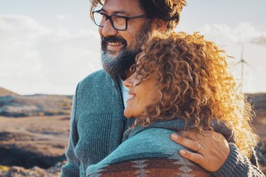Mutlu gezgin yetişkin çift, aşk ve macera dolu yaşam tarzıyla birlikte çöl sahili sahil şeridinde boş zaman aktivitelerinin tadını çıkarıyor. Erkek, dışarıda mutlu insanları kucaklıyor.