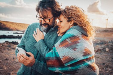 Erkek ve kadın açık havada seyahat aktivitelerinde cep telefonu bağlantısı kullanıyorlar. Mutlu yetişkin çift teknolojinin ve gezgin iletişimin tadını çıkarıyor. Seyahat macerası tatil yaşam tarzı