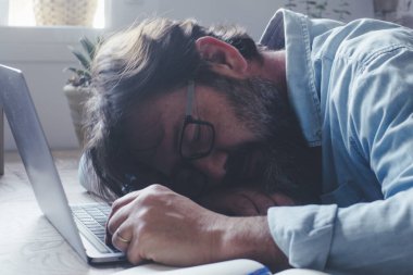 Ev işyerindeki laptopta uyuyan adam. Bilgisayar ve teknoloji kullanarak fazla çalışmaktan yorulmuş insanlar. Uykusuzluk. İş stresi. Sıkıcı iş. Evde bitkin bir erkek. Akıllı çalışma sorunları