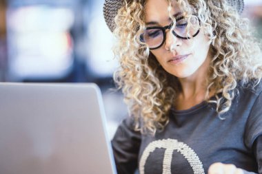 Bir kafede ya da havaalanı kapısında dizüstü bilgisayarla çalışan kadının portresi. Dijital göçebe ve modern işçi. Alternatif ofiste not defteri ve telefon kullanan kadınlar. Gözlüklü güzel bayan.