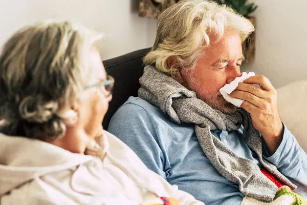 senior couple with cold and sneezing while having cold at home