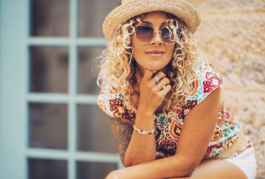 Evinin dışında gülümseyen ve ona bakan orta yaşlı kadın portresi. Çekici trend kadın turist şehir sokaklarında boş vakitlerinde dinleniyor. Neşeli yetişkin bayan.