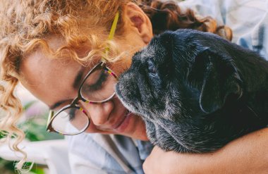 Sevgi dolu insanlar ve köpek hayvan konsepti. Mutlu yetişkin beyaz kadın ve siyah pug kucaklaşması ve şefkatle sevme. En iyi arkadaşlar sonsuza kadar konsept