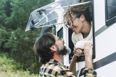 Yeşil Orman Parkı 'ndaki otoparkta bir karavan karavanı önünde konuşan kadın ve erkek gezgin. İnsanlar ve seyahat. Vanlife yaşam tarzı, Alternatif araç turu konsept hayatı
