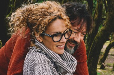 Erkek doğa parkında dizüstü bilgisayar kullanırken kadına sarılıyor. Dijital online seyahat aktivitelerinde bilgisayar izleyen çift kavramı. İnsanlar ve modern çalışma aktiviteleri