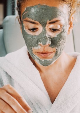 Krem maskeli, yaş karşıtı cilt bakımı karşıtı yetişkin güzel bir kadının portresi. Bakımlı ve sağlıklı bir yaşam tarzı olan kadınlar. Doğal ürünler el yapımı.