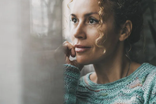 confident lady contemplate outside the window at home with dreaming and thoughtful expression on face. Portrait of adult female people in indoor thinking leisure activity alone with window light