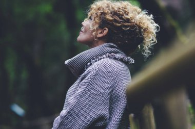 Rahatlamış ve mutlu özgür bir kadının yan portresi yeşil doğa parkının tadını çıkartıyor açık hava aktivitesi ayakta duruyor ve arka plana hayran. İnsan kavramı ve orman ve ahşap çevresiyle ilgili hisler