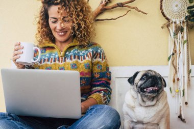 İnsanlar ve köpekler sonsuza kadar en iyi arkadaşlardır. Mutlu kadın gülümse ve sevgili arkadaşı köpek pug 'un yanında oturan dizüstü bilgisayarı kullan. Hayvan ve iş hayatı anı. Modern boş zaman aktivitesi