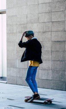 Şehirdeki kaykay kaykayı kullanarak hareket etmek için gri şehir duvarı arasında yeşil taşıma alternatifi. Gençler ve gençler için boş zaman etkinliği alanı ve konseptini kopyala.