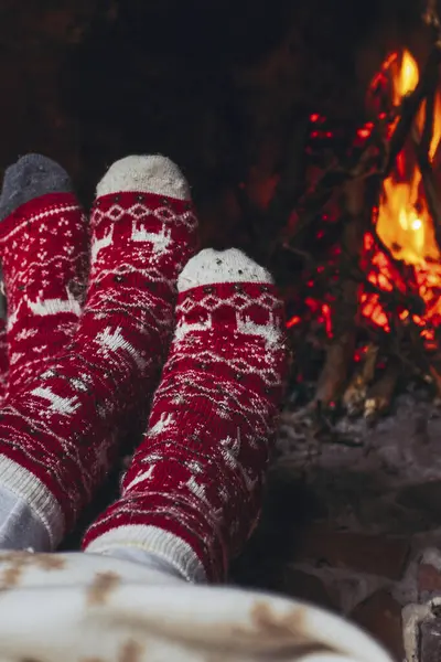 Pov of couple feet warming near fireplace at home or chalet room. Holiday vacation in christmas time. Romantic people enjoy relationship and tenderness looking fire indoor. Xmas socks red and white