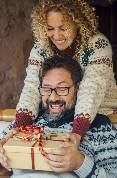 圣诞礼物交换时刻在家里 快乐的女人从沙发后面送给一个男人惊喜 背景是圣诞树和装饰品 情侣恋爱的假期 冬季庆祝活动 — 图库照片