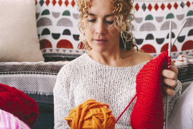  woman at home sitting on the ground busy in knitting hobby work activity. Indoor leisure female people with wool. Creative time concept. Learning new things. Adult lady spending time in apartment