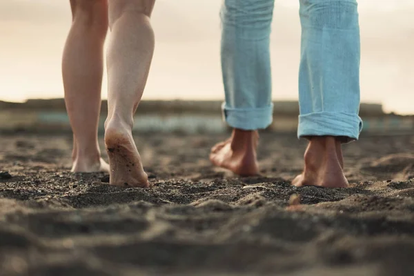 Close up and legs view for man and woman walking together on the ground in barefoot natural style. Concept of love and life together. Nudism. Couple of people walk. Sky in background. Travel.