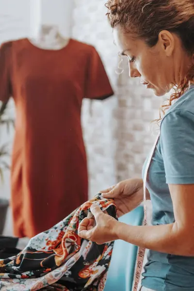 Seamstress at home workshop working with clothes in fashion industry. Professional tailor making dress. Side view of woman in hobby and leisure activity indoor alone. Concept of alternative job life