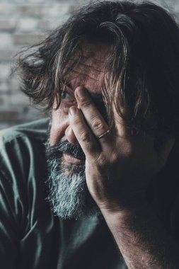 Çaresiz ve stresli bir adam elleriyle yüzüne dokunuyor ve dışarı bakıyor. Sorunlar ve evdeki endişeli insanlar. İlişkimiz bitti ve kocanın aşkı ayak parmaklarının ucunda kanepede oturuyor. Ekonomi hatası